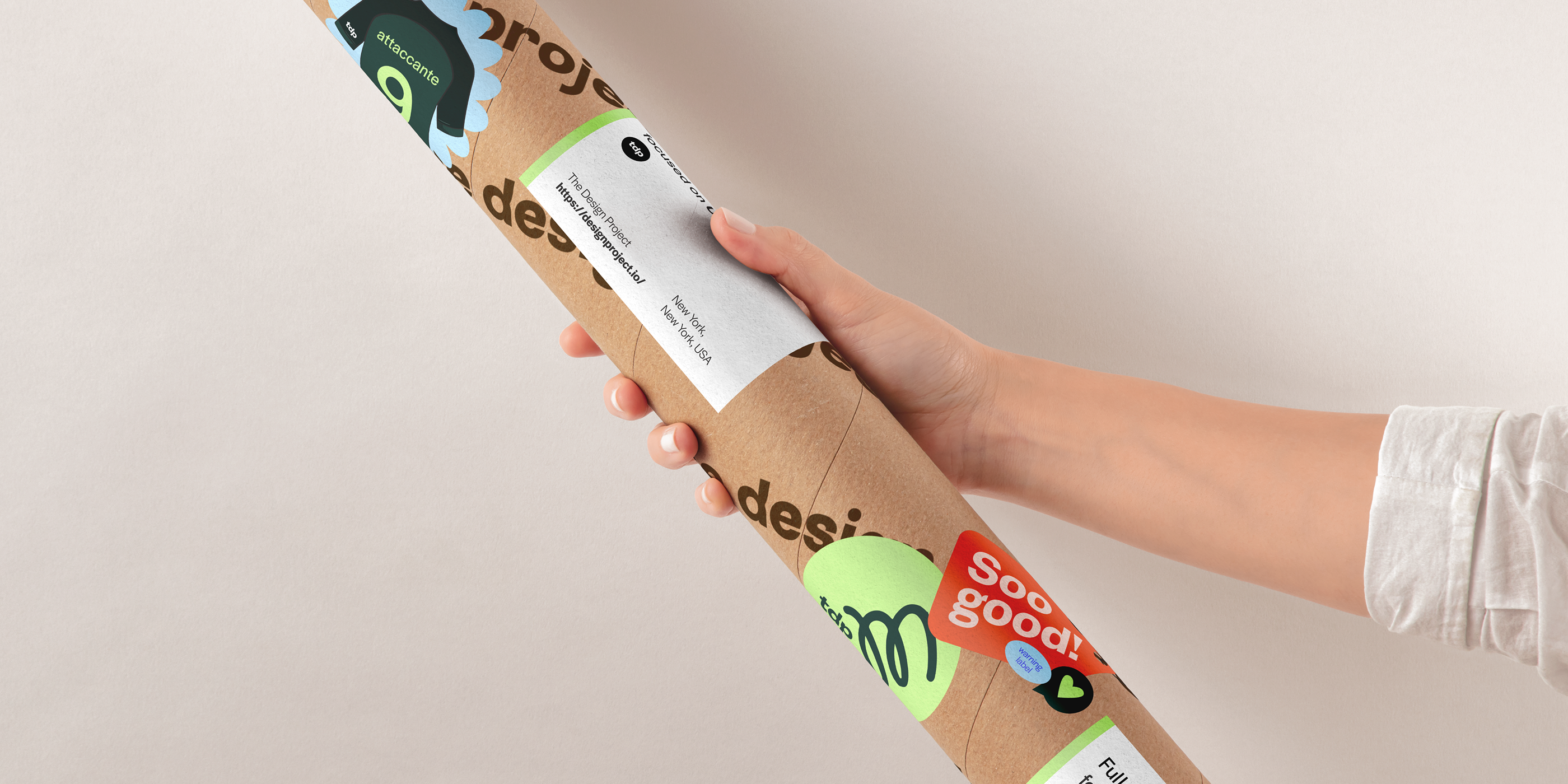 TDP branded packaging — hand holding a kraft cardboard mailing tube covered in TDP stickers and brand elements
